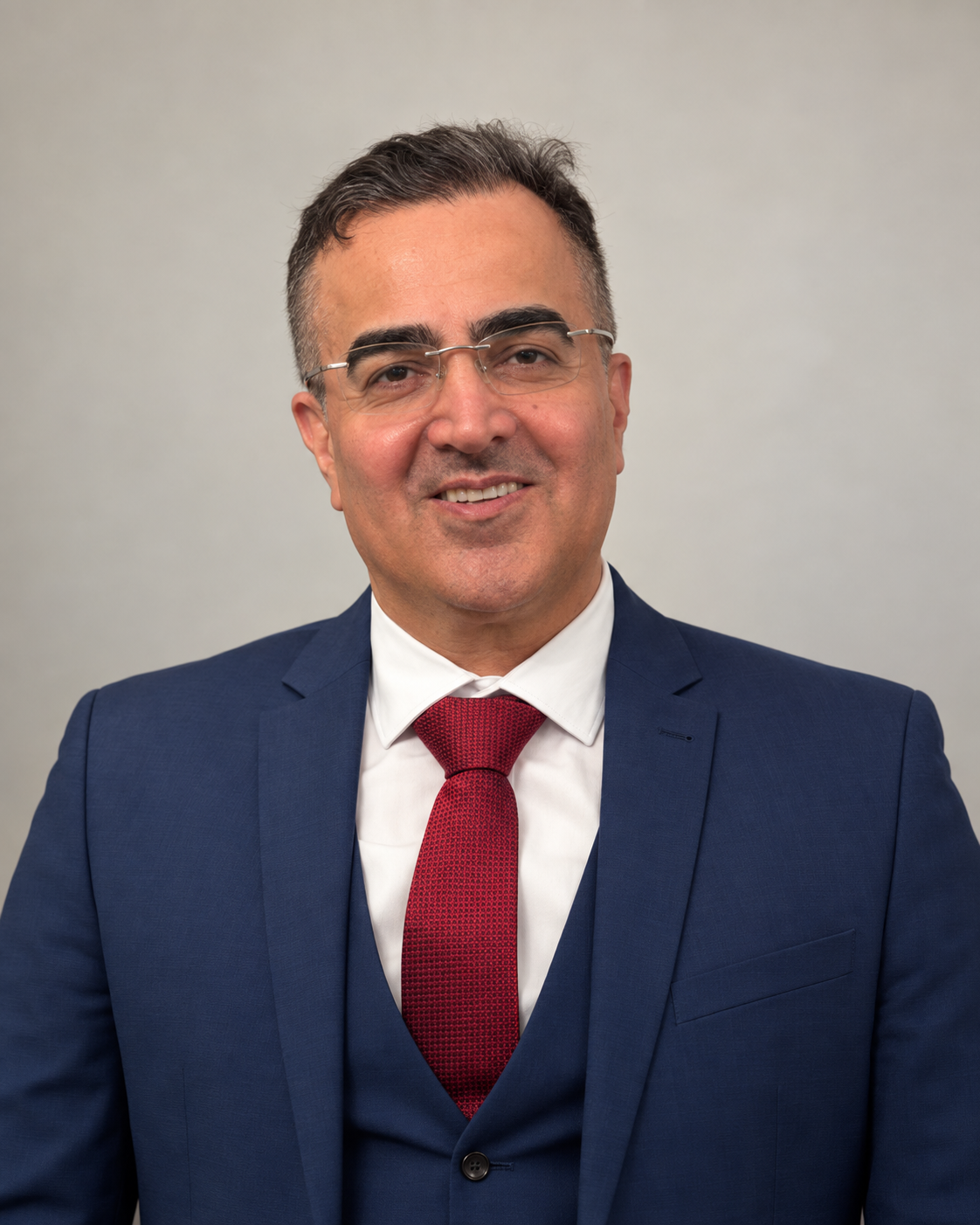 Mr Peyman Bakhshayesh, Consultant Trauma and Orthopaedic Surgeon, wearing a blue suit and red tie
